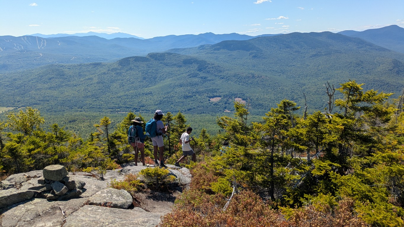 Kids hiking down a mountain with a nice view in the background.